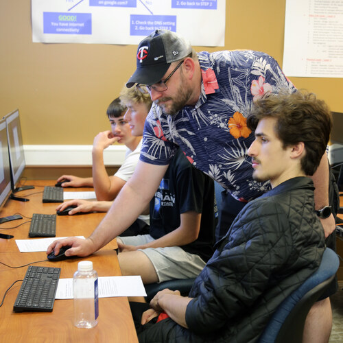 Instructor helping students at computers in an IT and networking lab