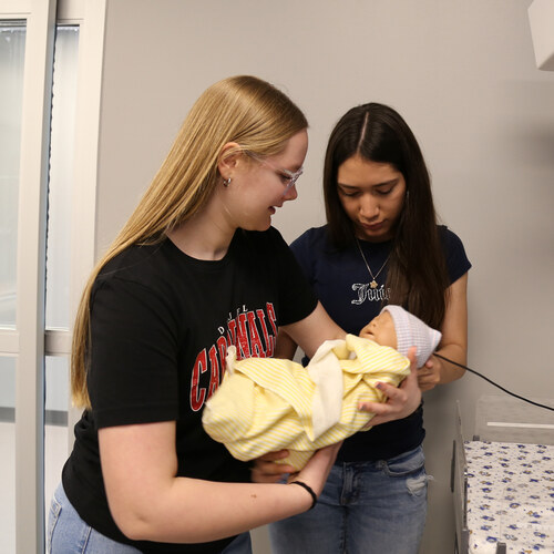 Nursing students practicing newborn care with a simulation baby